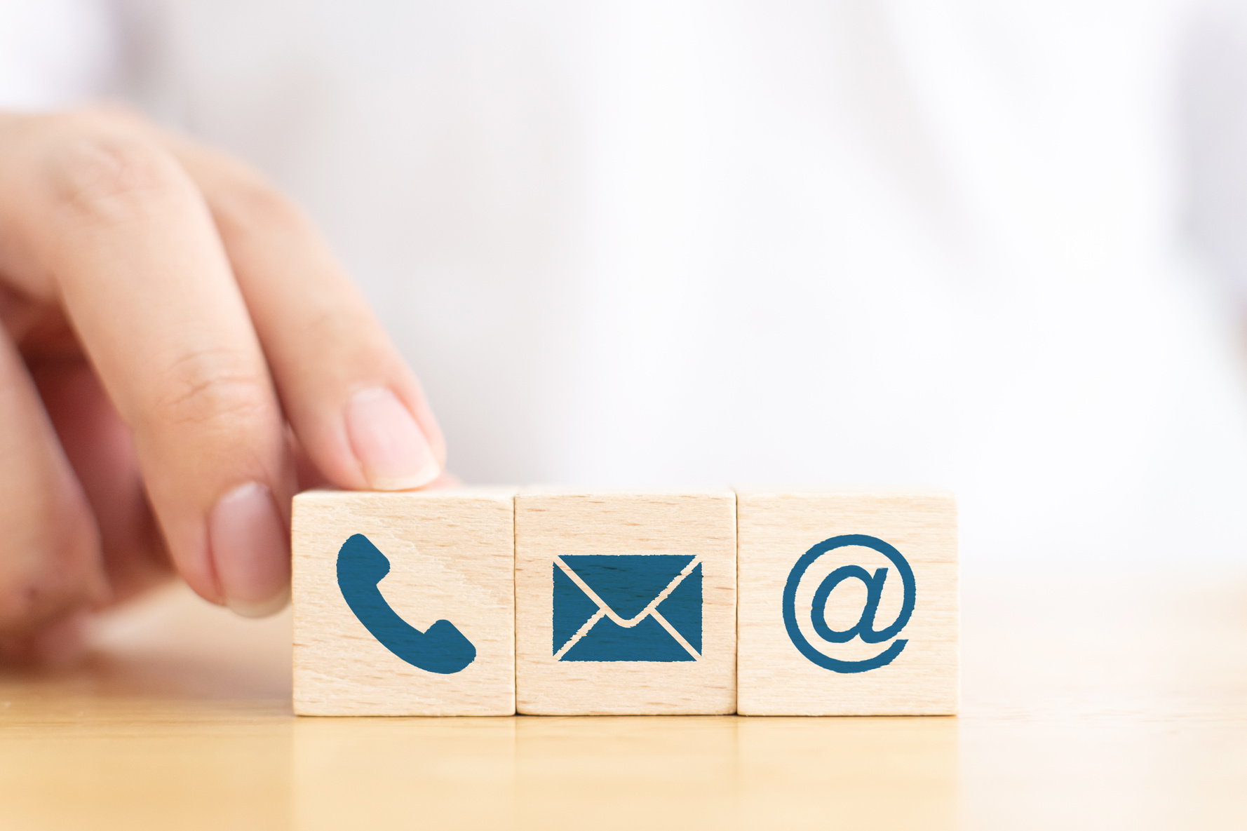 Businessman hand choose wooden block cube symbol icon telephone, envelope email and address sign. Website page contact us or e-mail marketing concept